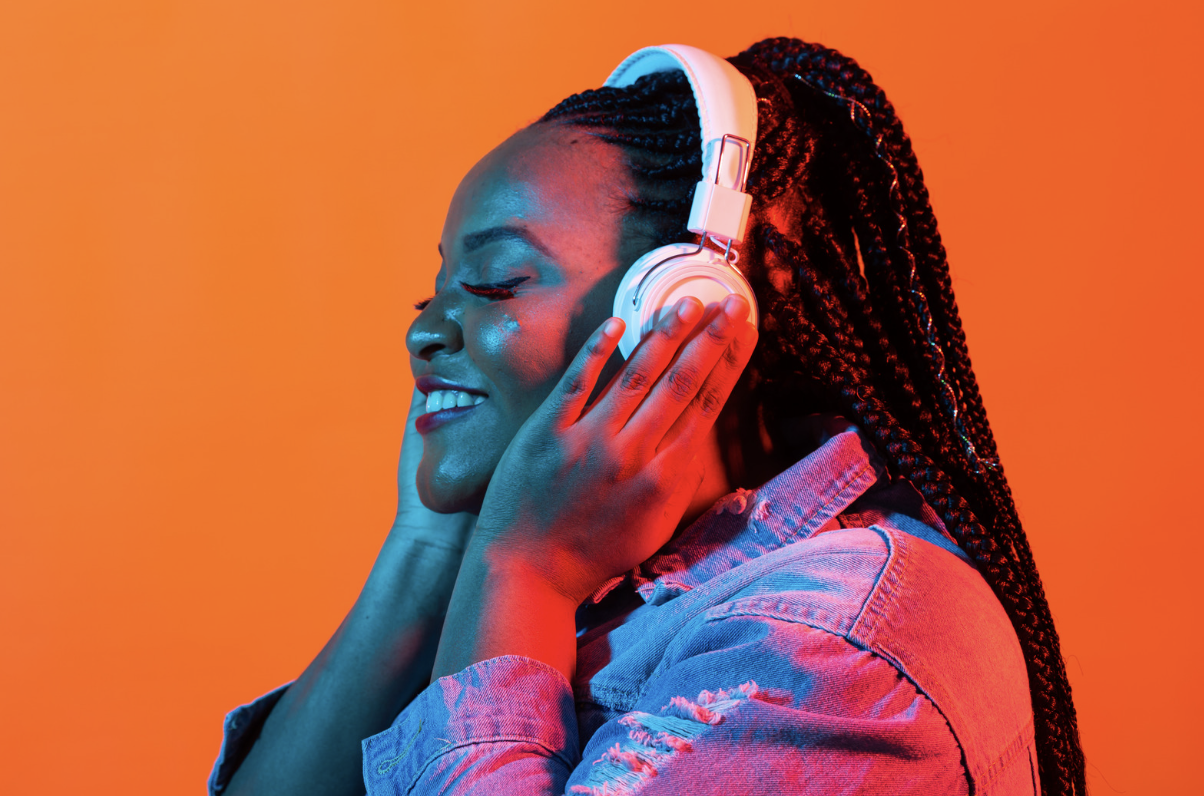 Image shows women smiling with headphones on listening to binaural beats, demonstrating the benefits on welling being and cognitive function of binaural beats.